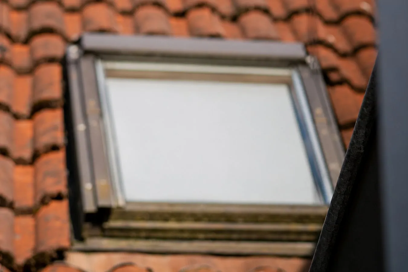 Gammalt tegeltak med takfönster och slitna plåtbeslag som kontrolleras vid en takbesiktning